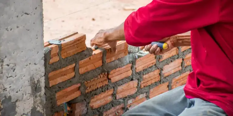 Maçon montant un mur en briques